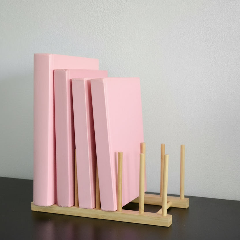 Rosa bøker i en bambus bokholder.