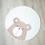 Et rundt, hvitt teppe med en bamse som motiv