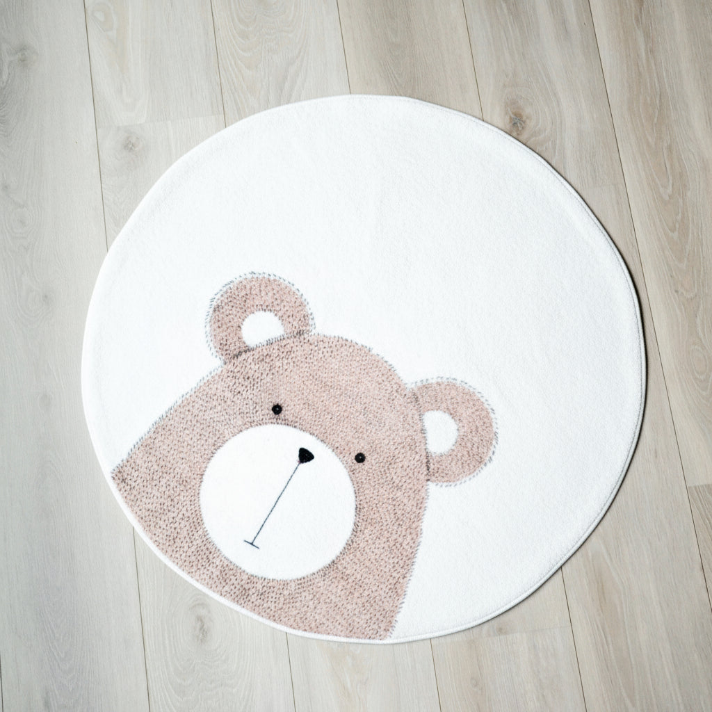 Et rundt, hvitt teppe med en bamse som motiv