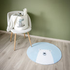 Et rundt, blått teppe med en isbjørn, sammen med en stol med barneleker. 