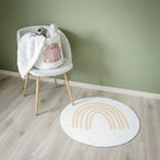 Et rundt teppe med regnbuemotiv som ligger på et gulv, sammen med en stol med barneleker.